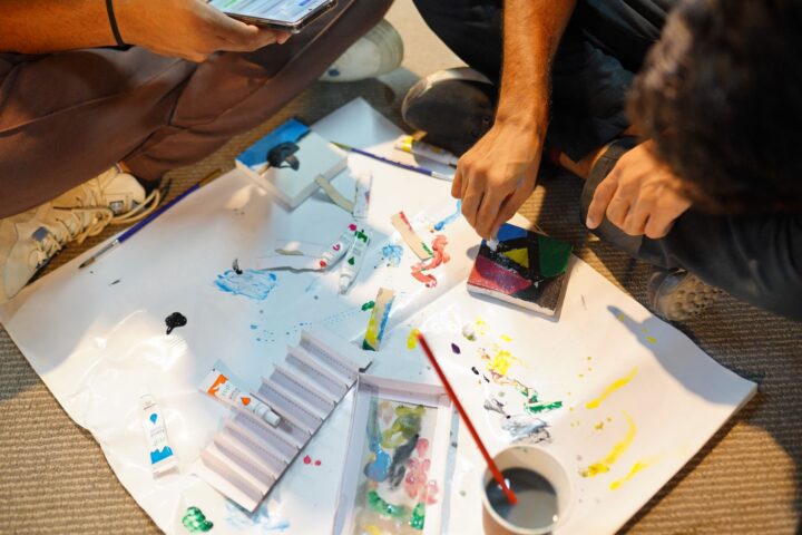 Volwassenen namen deel aan een praktische schilderworkshop, waarbij ze kleuren mengden en binnen kunstwerken maakten.