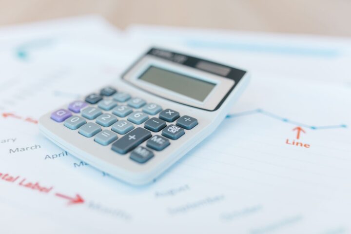 Close-up van een rekenmachine op financiële documenten met grafieken en analysepapieren.
