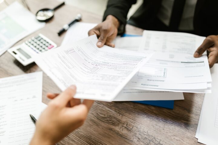 Twee professionals wisselen documenten uit in een kantooromgeving, met de nadruk op papierwerk en data-analyse.
